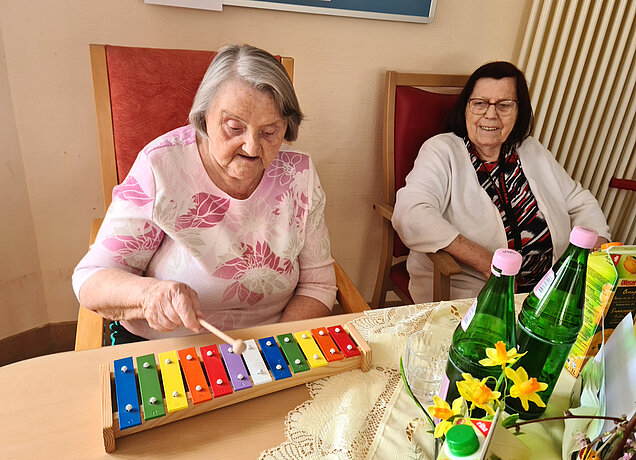 Frau macht Musik auf dem Xylophon und eine andere Frau schaut zu