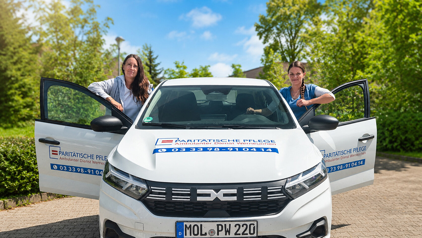 Mitarbeitende des ambulanten Pflegedienstes Werneuchen stehen neben einem Dienstfahrzeug der Paritätischen Pflege.