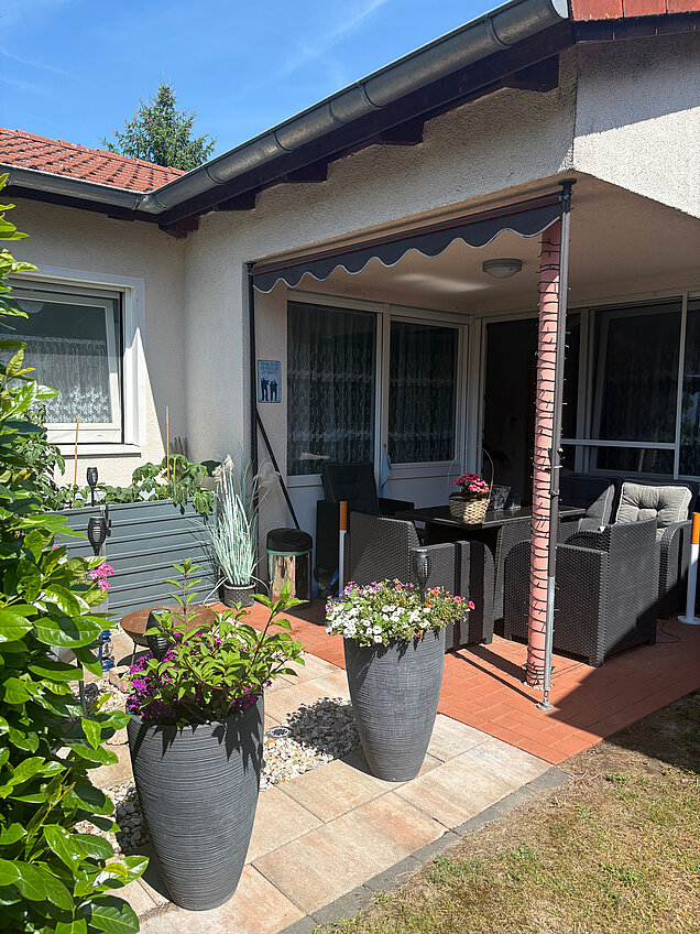Überdachte Terrasse und bepflanzte Blumenkübel